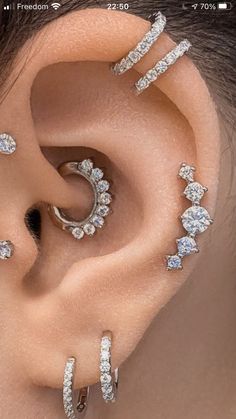 an ear with three different types of piercings on it's sides and two rows of diamonds in the middle