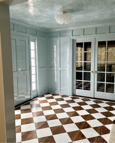 an empty room with large checkered flooring and glass doors leading to another room