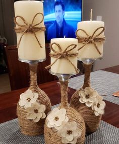 three candles are sitting on a table with twine and burlock wrapped around them