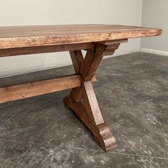 a large wooden table sitting on top of a cement floor next to a white wall