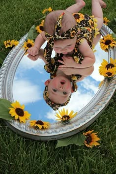 a baby is reflected in a mirror with sunflowers