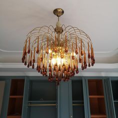 a chandelier hanging from the ceiling in a room with blue cupboards and shelves