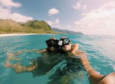 two people swimming in the ocean with snorkels on their heads and one person wearing goggles