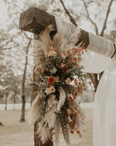 the bride is holding her bouquet with feathers and flowers on it as she walks down the aisle