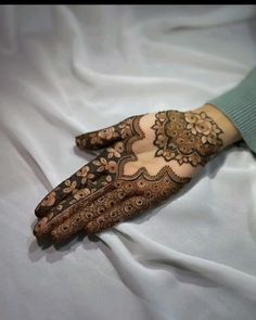 a woman's hands with hennap on top of white sheeted bed