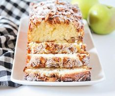 a white plate topped with sliced cake next to an apple