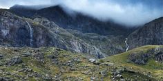 the mountains are covered in clouds and grass