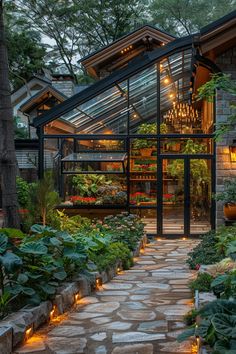 an outdoor garden with lots of plants and lights in the house's entry way