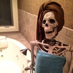 a skeleton sitting in a bathtub next to a tub with a towel on it