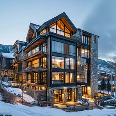 a large building with lots of windows in the middle of snow covered ground and mountains behind it