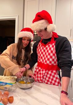 two people in santa hats preparing food on a kitchen counter