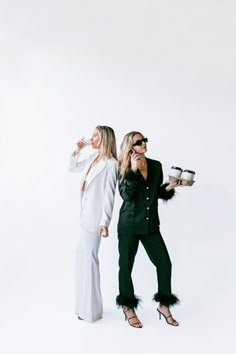 two women standing next to each other in front of a white background