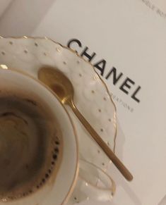 a coffee cup and saucer sitting on top of a table next to a book