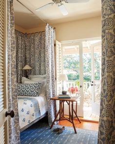 a bed room with a neatly made bed next to a window and a ceiling fan