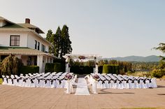 a wedding ceremony in front of a large white house with lots of chairs set up