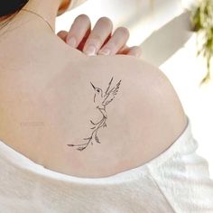 a woman's back shoulder with a small bird tattoo on the left side of her upper arm