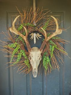 a deer's head is mounted on the front door with green leaves and branches