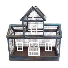 a bird cage with two birds in it and a house on the top of it