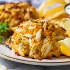 crab cakes on a plate with lemon wedges and parsley