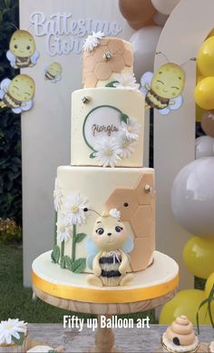 a three tiered cake sitting on top of a table next to balloons and bunting