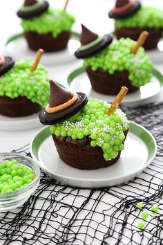 some cupcakes with green frosting and chocolate decorations on them are sitting on plates