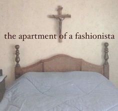 a bed with a cross on the wall above it that says, the apartment of a fashionistaa