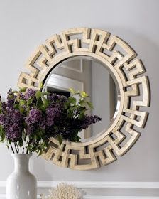 a vase filled with purple flowers sitting next to a mirror on a wall above a table