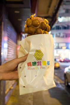 a person holding up a bag with some food on it in front of a building