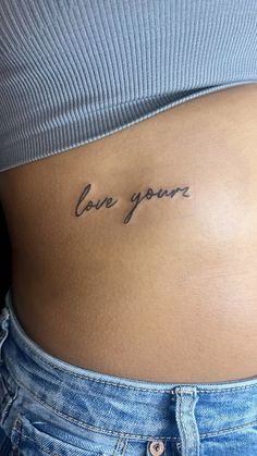 a woman's stomach with the words love you written on her lower back tattoo