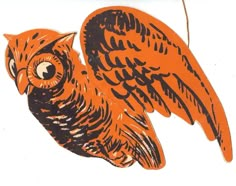 an orange and black owl ornament hanging from a string on a white background