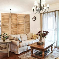 a living room filled with furniture and a chandelier hanging from the ceiling over a wooden coffee table