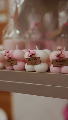 small candles with pink flowers on them sitting on a shelf