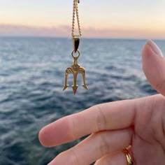 a hand holding a gold necklace with a star trek symbol hanging from it's end