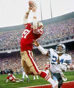 a football player jumping up into the air to catch a ball in front of another player