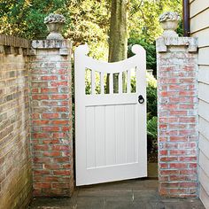 an open white gate leading to a brick house