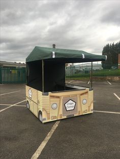 an old fashioned food truck is parked in a parking lot with a green cover over the top