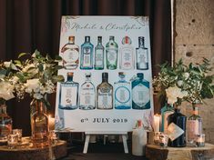 a table topped with lots of bottles of alcohol next to vases filled with flowers