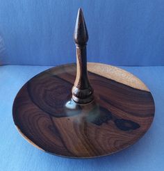 a wooden plate with a metal tip on it sitting on a blue tableclothed surface