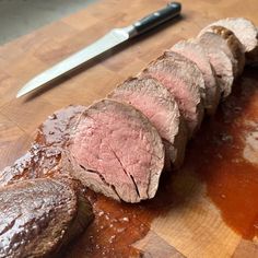 sliced meat sitting on top of a cutting board next to a knife