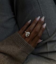 a close up of a person's hand with a ring on their finger, wearing a sweater