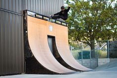 a man riding a skateboard up the side of a ramp on top of a wooden ramp