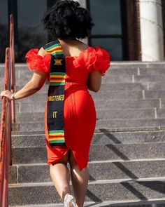 a woman in a red dress walking up some steps with her back to the camera