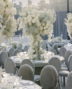 the tables are set with white flowers and silver chairs