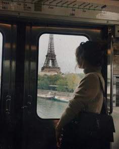 a woman looks out the window at the eiffel tower