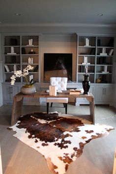 a living room filled with furniture and a cow hide rug