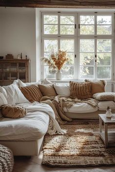 a living room filled with lots of furniture and pillows on top of a wooden floor