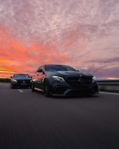 two mercedess driving down the road at sunset