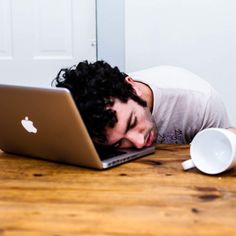 a man laying on the floor with his head down in front of an apple laptop