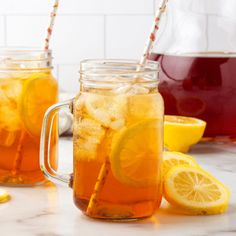 two mason jars filled with lemonade, ice and water next to sliced lemons