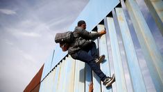 a man climbing up the side of a building with a backpack on his back and one foot in the air